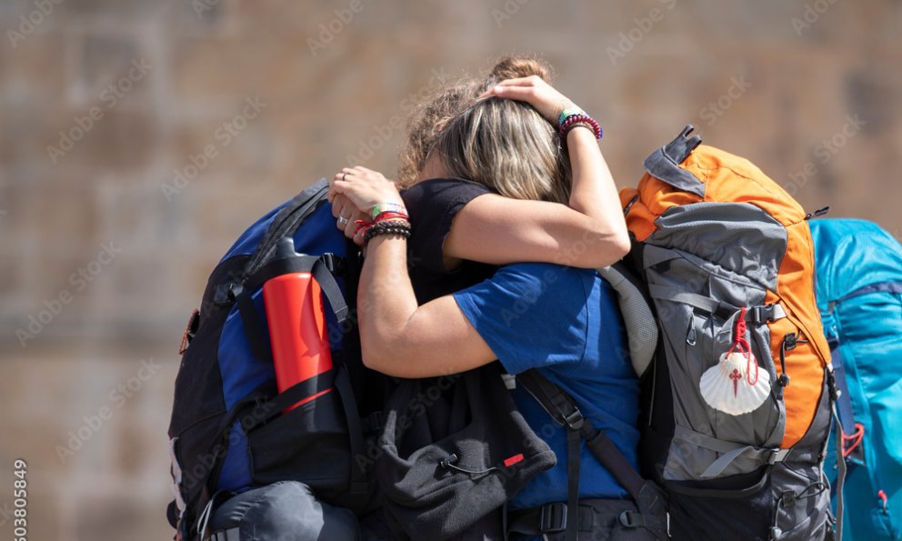 Deux pèlerins avec tenue de sport et sac à dos qui s’enlacent