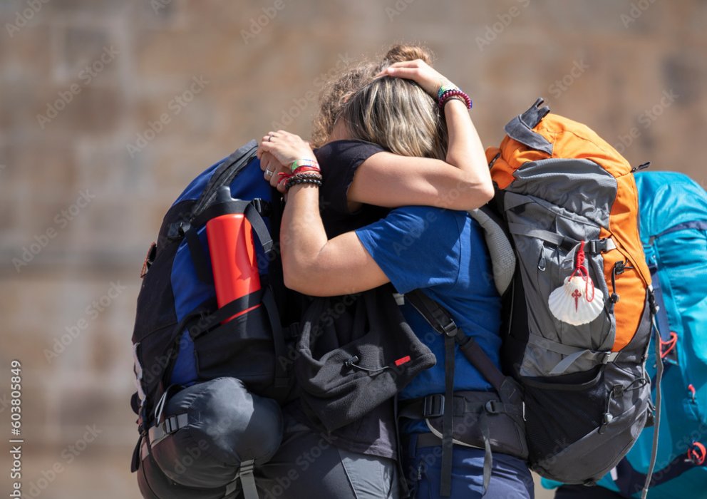 Deux pèlerins avec tenue de sport et sac à dos qui s’enlacent